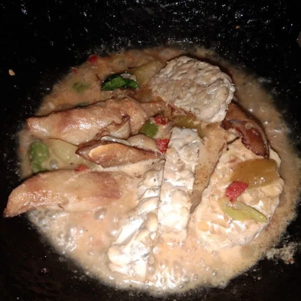 Masukkan ikan pari dan tempe, ratakan lalu ungkep sampai bumbu meresap.