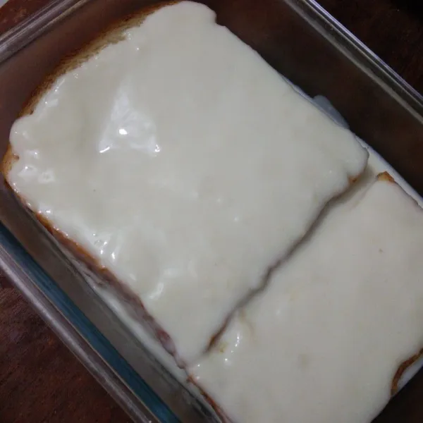 Susun roti di dalam wadah lalu tuang adonan, jangan lupa taburkan keju parut diatasnya .