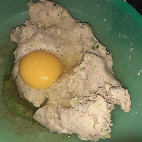 Ceplokkan telur ke adonan tempe, lalu aduk rata.