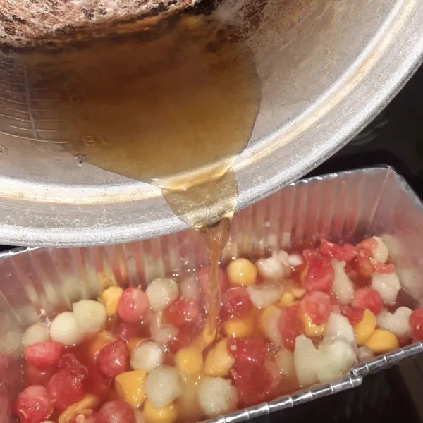 Tuangkan air puding ke dalam cetakan yang berisi potongan buah.