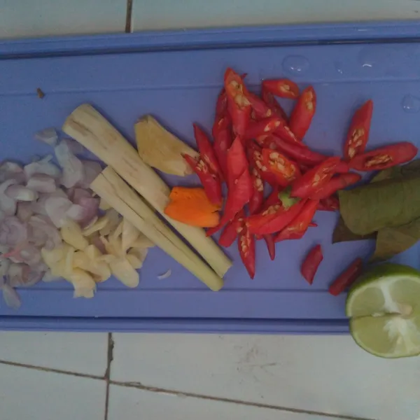 Iris-iris bawang merah, bawang putih, cabe merah keriting, jahe geprek, kunyit, dan serai. Siapkan 1/2 buah jeruk nipis dan daun jeruk.
