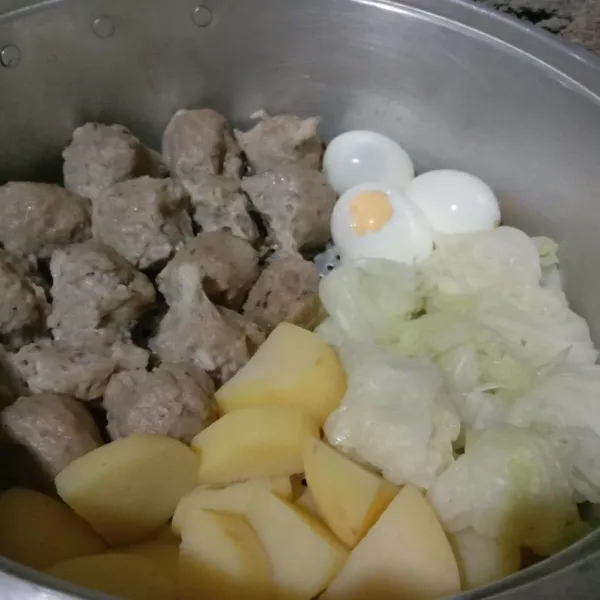 Tiriskan siomay lalu taruh di kukusan bersama telur, kentang, dan kol, kukus kembali sampai kentang matang.