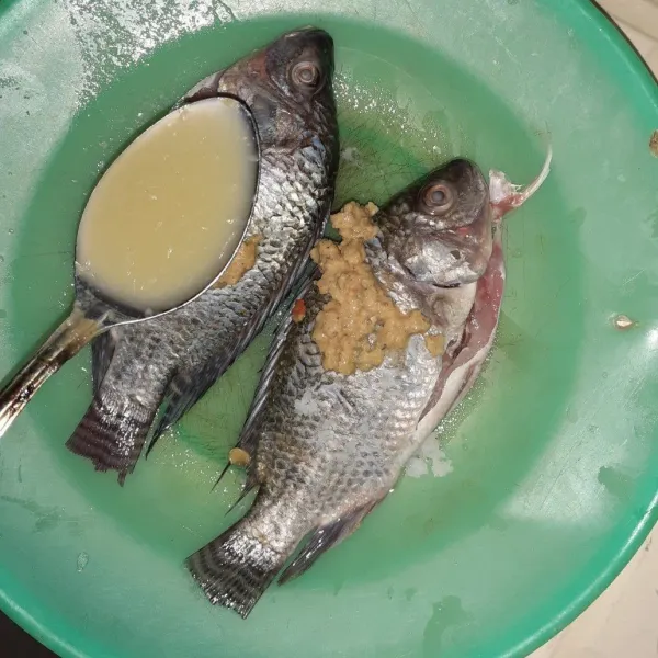 Bersihkan ikan nila, lumuri dengan bumbu halus, air lemon, dan garam.