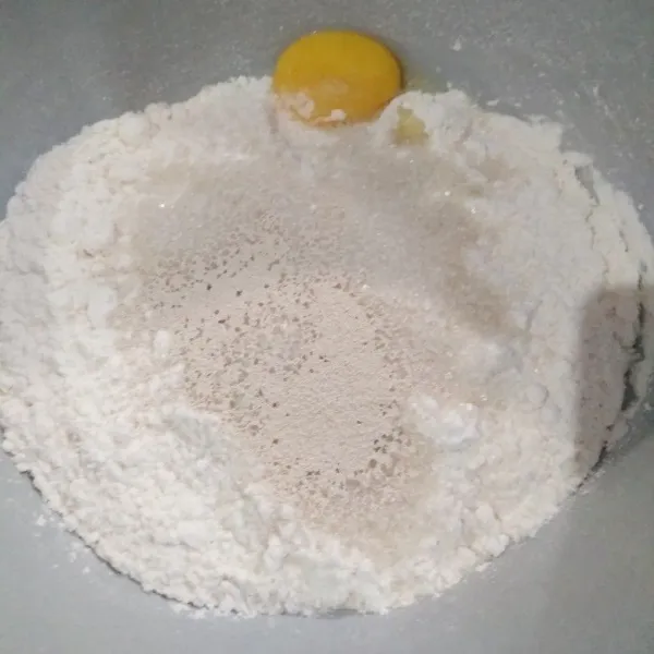 Masukkan tepung terigu, ragi instan, gula pasir, dan kuning telur ke dalam mangkok.