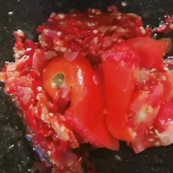 Setelah bawang dan cabai tercampur, iris tomat tambahkan garam, ulek sampai tercampur rata.
