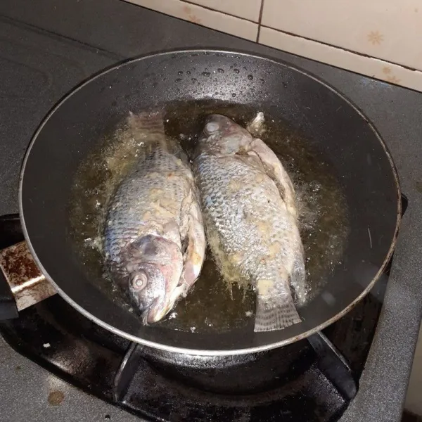 Panaskan minyak kemudian goreng ikan nila hingga berwarna keemasan, angkat dan tiriskan terlebih dahulu.