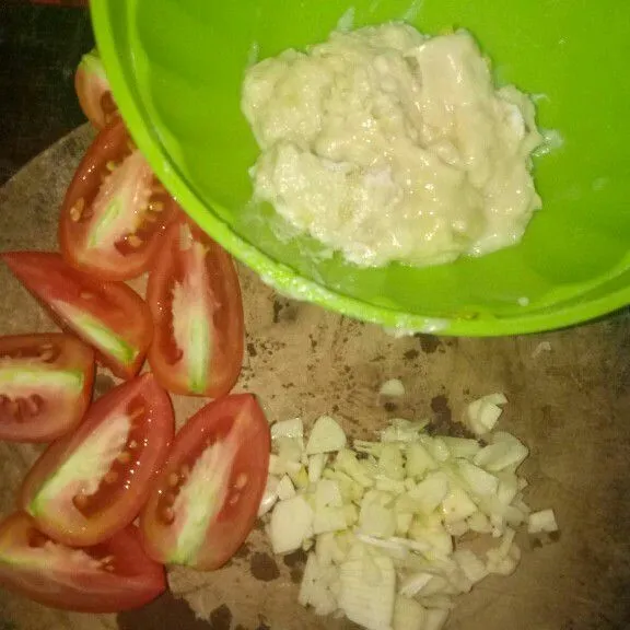 Siapkan bahan-bahan berupa bawang putih diiris tipis untuk menumis, tempoyak dari durian yang telah dipisahkan dari bijinya, dan tomat yang telah diiris.