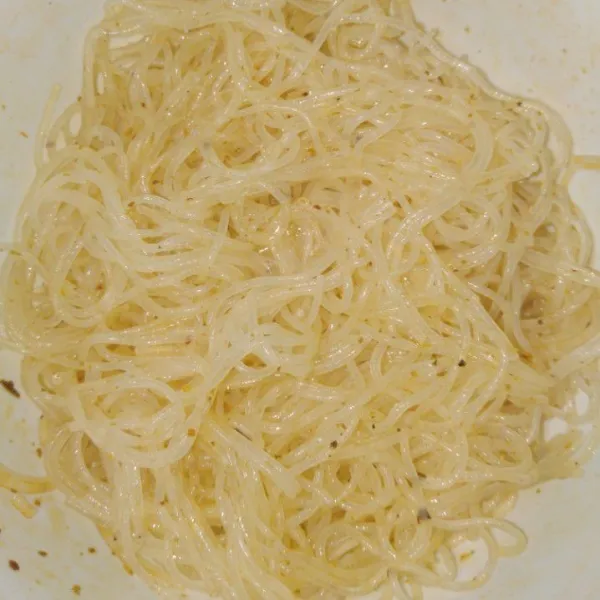 Rebus bihun sampai matang dan tiriskan. Campur bihun dengan minyak sayur dan setengah bumbu instannya.