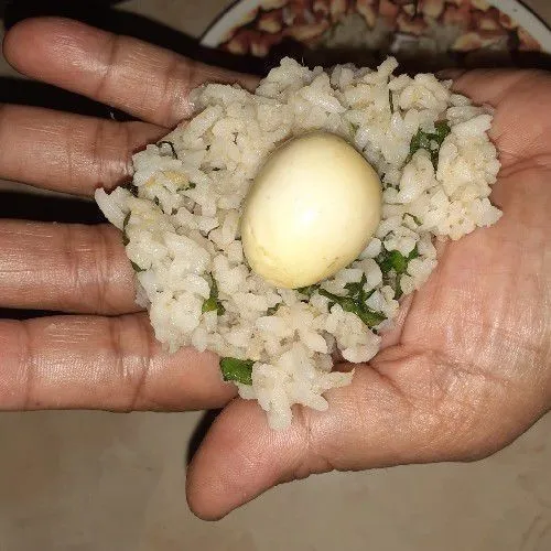 Kepal-kepal adonan nasi, beri isian telur puyuh, lalu bentuk bulat-bulat.