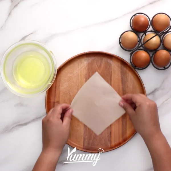 Siapkan dua lembar kulit lumpia, lalu rekatkan dengan putih telur.