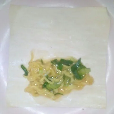 Taruh isian mie, daun bawang dan telur diatas kulit martabak.