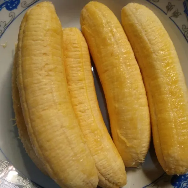 Kupas pisang, kemudian gosok-gosok permukaannya dengan kulit pisang bagian dalam. Ini supaya hasil pisang gorengnya cantik.