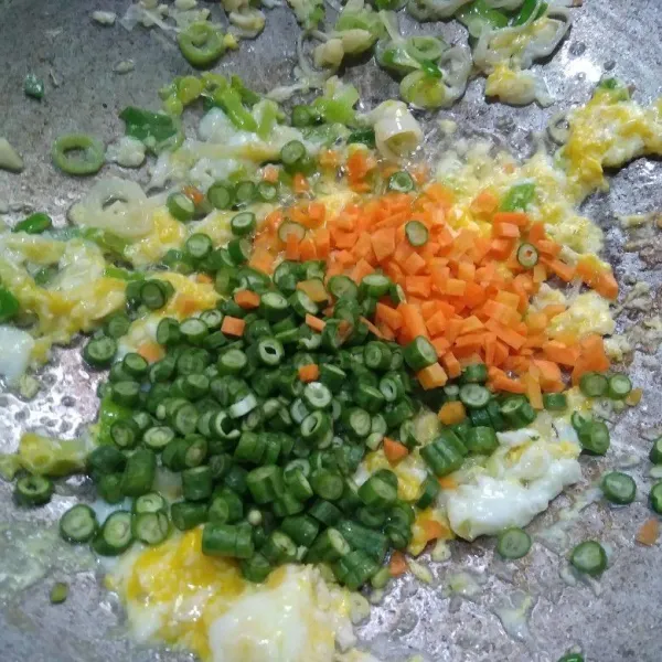 Pecahkan telur ke dalam wajan, bikin orak-arik kemudian masukkan wortel dan kacang panjang, aduk-aduk hingga layu.