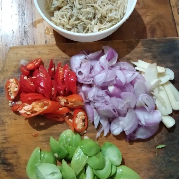 Siapkan bumbu, iris tipis duo bawang, cabe rawit, belah dua petai, dan bilas sekali ikan teri.