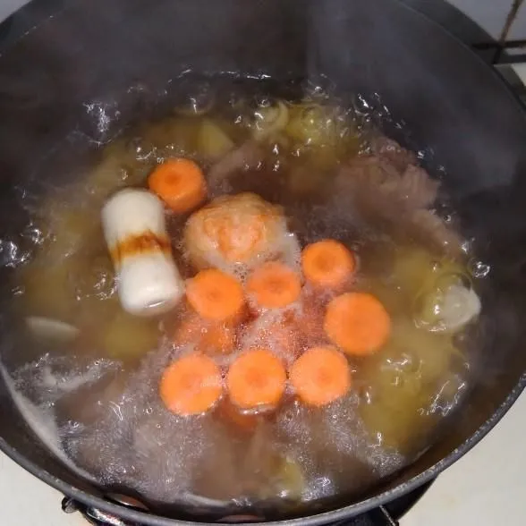 Masukkan kentang, bakso ikan, wortel, dan bawang putih geprek.
