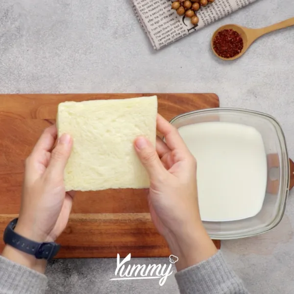 Celupkan roti tawar ke dalam susu sebentar saja, lalu pipihkan roti dengan rolling pin atau tangan.