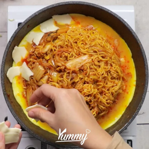 Beri sobekan keju di atas telur, masak hingga telur matang sesuai selera. Mie Goreng Kimchi Telur Keju siap disajikan dengan bahan pelengkap sesuai selera.