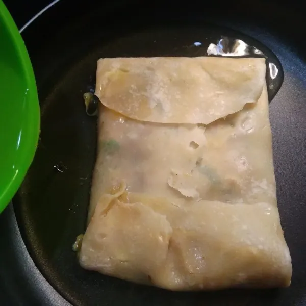 Lipat kulit martabak seperti amplop menutupi adonan isian, beri minyak goreng sisa rendaman adonan tadi, goreng hingga kokoh.