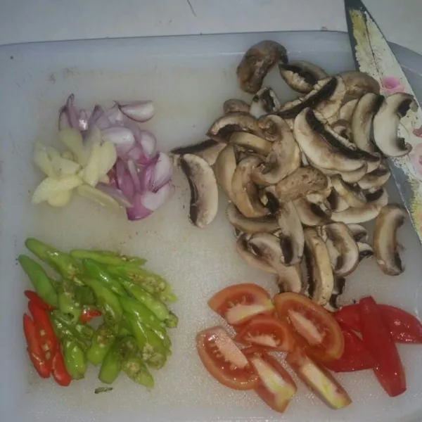 Iris jamur kancing, bawang merah, bawang putih, cabe rawit, dan tomat.