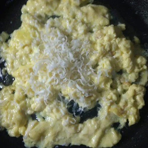 Masukkan telur dalam teflon, orak-arik sampai setengah matang. Tambahkan keju parut. Orak-orik lagi sampai matang.