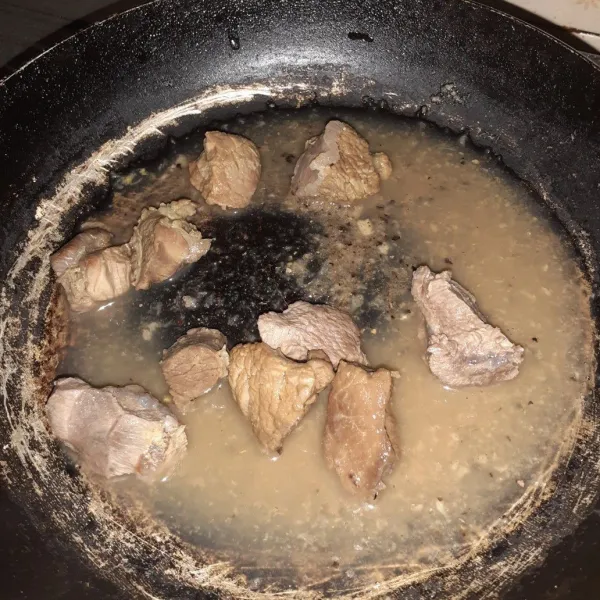 Panaskan air, masukkan bumbu halus dan daging.