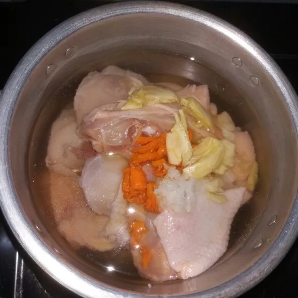 Cuci bersih ayam, tempatkan dalam panci lalu beri air hingga ayam tenggelam. Tambahkan kunyit dan bawang putih yang sudah dikeprek, juga bubuhkan garam.