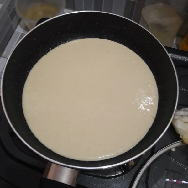 Panaskan teflon dengan api kecil, olesi dengan sedikit margarin. Tuang adonan, tunggu sampai adonan berpori.