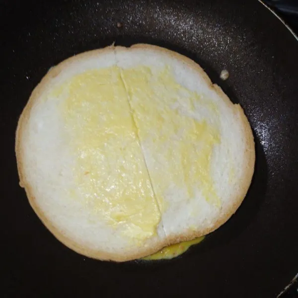 Saat telah setengah matang, tempelkan roti tawar agar merekat. Olesi bagian atas roti dengan margarin. Jika sudah matang, balik dan angkat.