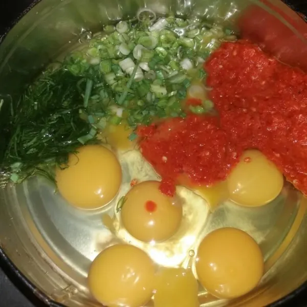 Siapkan telur dalam wadah, tambahkan bumbu halus, daun bawang, dan juga daun kunyit. Lalu aduk hingga tercampur rata.