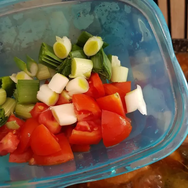 Setelah air sedikit menyusut, masukkan potongan tomat dan daun bawang, aduk rata. Masak kembali hingga air menyusut.