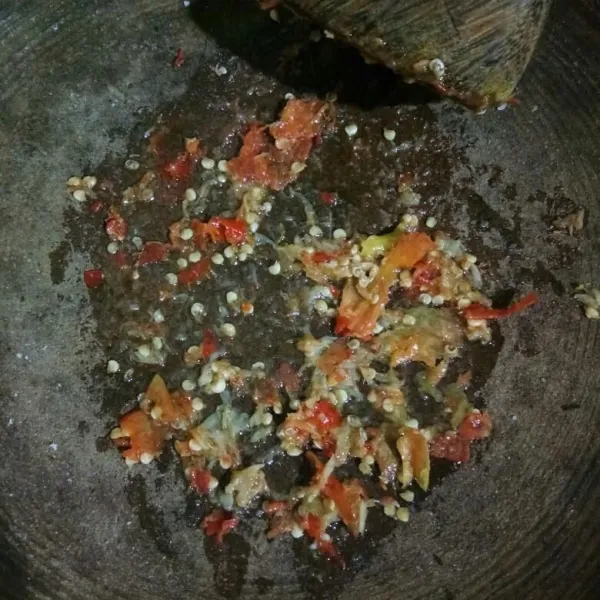 Masukkan cabe, bawang putih goreng, dan garam lalu ulek kasar. Beri 1 sdm minyak panas bekas menggoreng telur tadi, ulek rata.