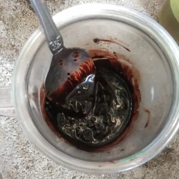 Masukkan coklat bubuk dan air panas ke dalam wadah, aduk rata sampai menjadi pasta coklat.