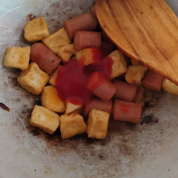 Masukkan sosis dan tahu goreng, lalu bumbui dengan saos tomat, saos tiram, garam, gula pasir, dan penyedap. Aduk rata.