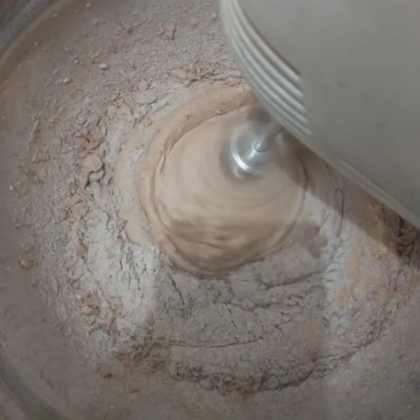 Turunkan kecepatan mixer ke yang paling rendah. Masukkan campuran tepung 3 kali secara bertahap.