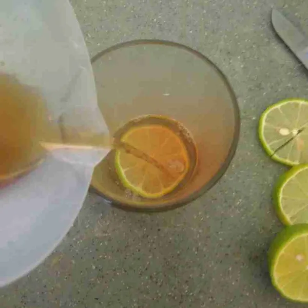 Dalam gelas saji, masukkan irisan lemon sesuai selera. Tambahkan air teh serai.