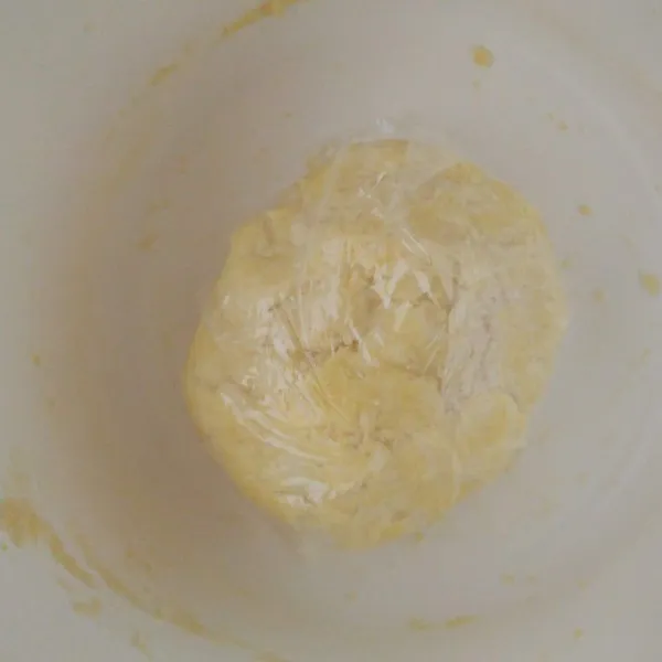 Masukkan air es sedikit demi sedikit sambil diaduk pelan agar air terserap sempurna. Uleni adonan sebentar saja untuk membulatkan adonan kemudian bungkus menggunakan plastik wrap. Istirahatkan adonan dalam kulkas selama 30 menit.