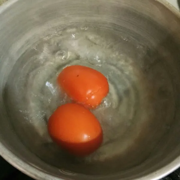 Rebus tomat dengan air hingga mendidih, diamkan beberapa saat.