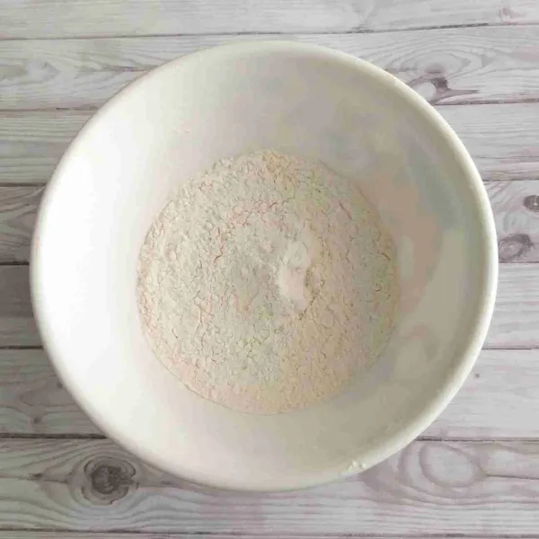 Buat adonan celupan dengan cara ayak tepung dengan saringan hingga hanya tersisa butiran halus di dalam mangkuk, lalu campurkan gula pasir dan vanila.