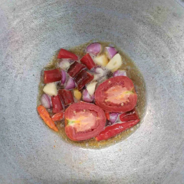 Goreng bawang merah, bawang putih, cabai merah, cabai rawit, dan tomat sampai layu.