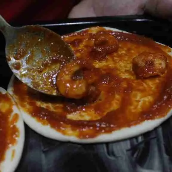 Siapkan roti pizza, olesi loyang dengan margarin, letakkan pizza diatas loyang lalu beri saus diatas pizza.