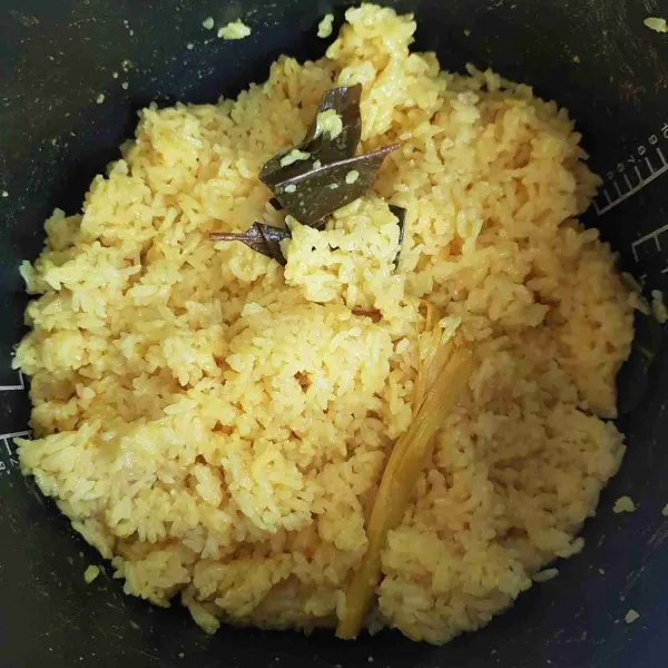 Masukkan dalam rice cooker, tekan tombol cook. Biarkan hingga matang. Setelah matang, aduk rata nasi kuning.