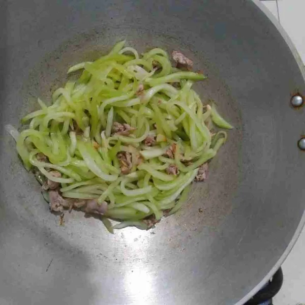 Masukkan irisan labu, tambahkan air lalu aduk hingga rata.