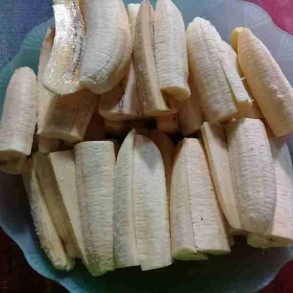 Kupas pisang lalu belah menjadi empat bagian.