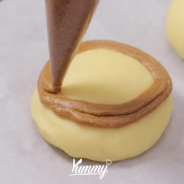 Tuangkan bahan toping di atas roti yang telah mengembang berbentuk spiral.