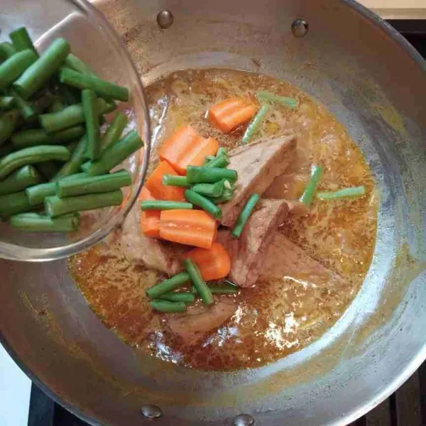 Masukkan tahu goreng, wortel, dan kacang panjang masak hingga sayur empuk.