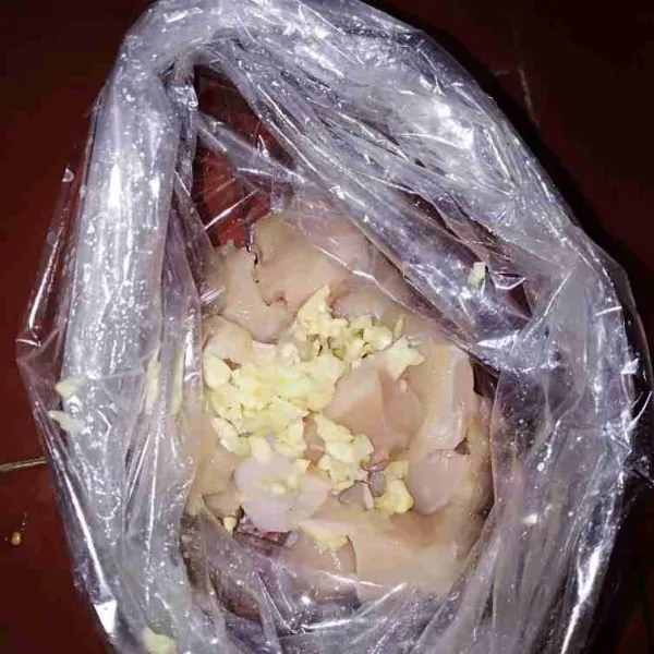 Masukkan ayam dalam plastik kemudian tambahkan bawang putih.