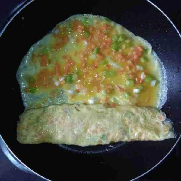 Jika permukaan telur mulai kering, gulung sambil sedikit di tekan hingga ¾ bagian, lalu tuang kembali kocokan telur.