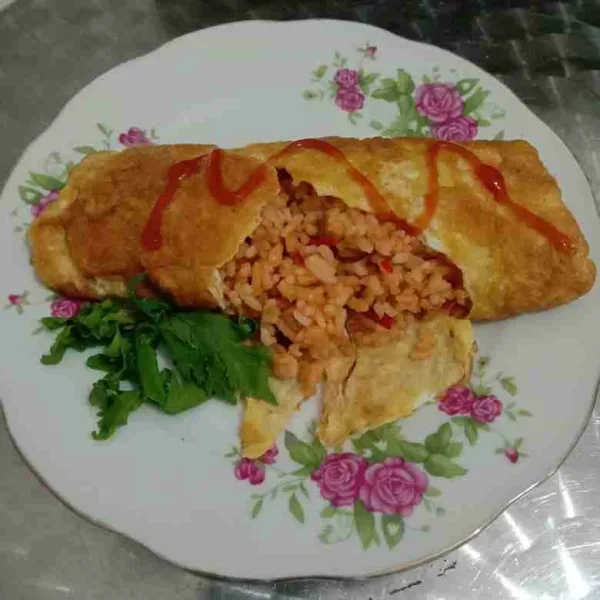 Balik omelette dengan posisi lipatan di bagian bawah. Sajikan omurice dengan saos tomat.