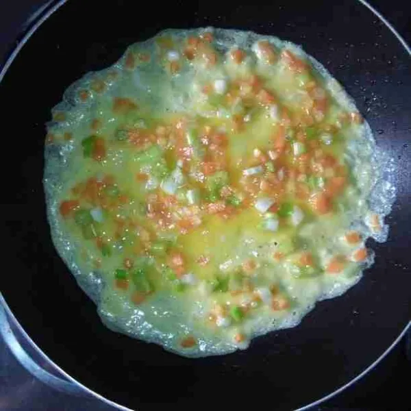 Panaskan pan dengan api kecil beri sedikit minyak lalu tuang ¼ bagian telur.