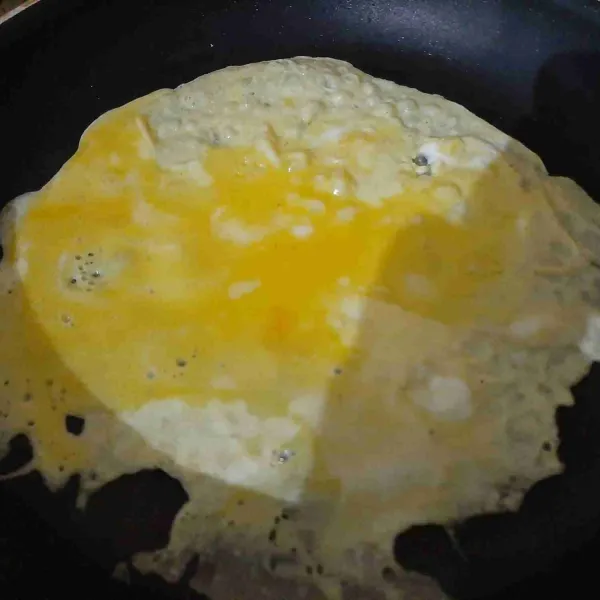 Panaskan teflon dan tuang telur, tunggu sampai bagian bawah matang.